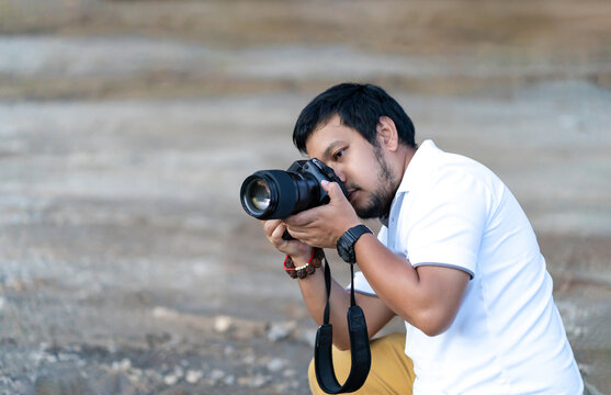 Professional Asian beard - mustache Camera man posture and focus in viewfinder and LED screen on mirrorless camera medium format in construction concrete area.
