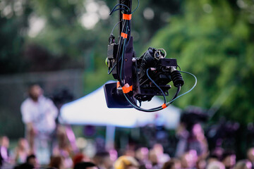 Shallow depth of field (selective focus) image with a professional video camera on a crane during an outdoor event.