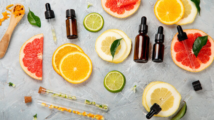 Bottle of essential aroma oils with citrus on light gray background.