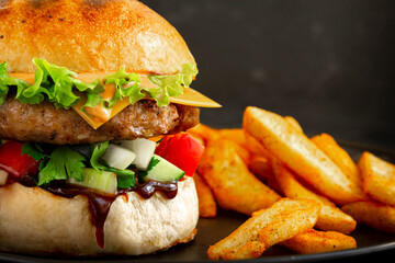 Extra Close-up of Fresh tasty burger with pork, salad, cheesee, sauces and with french fries. Fat unhealthy street food.