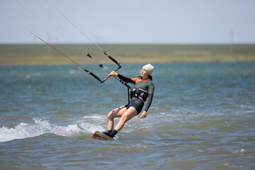 Young brunette girl enjoyes kitesurfing. Fresh natural summer, leisure and people concept.