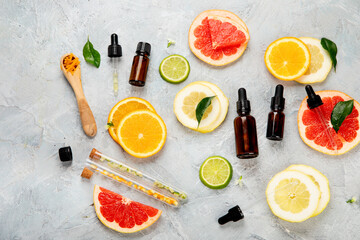 Bottle of essential aroma oils with citrus on light gray background.