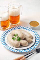 Munich white sausage with sweet mustard and beer in glass on paper plate.