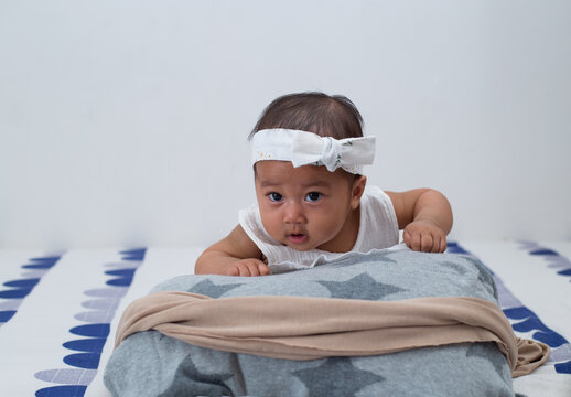 Closeup portrait of southeast asian baby girl with white dress and headband. 