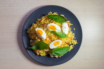 A plate of kedgeree with eggs and mint leaves.