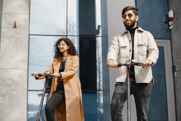 Obraz na płótnie Canvas Interracial young couple with scooters in the city background
