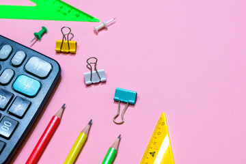 School supplies on a pink background. View from above. Copy space. Office and calculator items for study and work