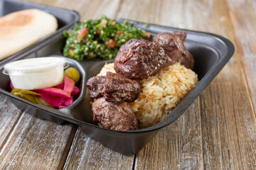 A closeup view of a beef kabob combo in a styrofoam to-go container.