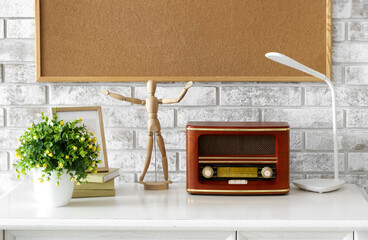Retro radio receiver with mannequin and houseplant on table near brick wall