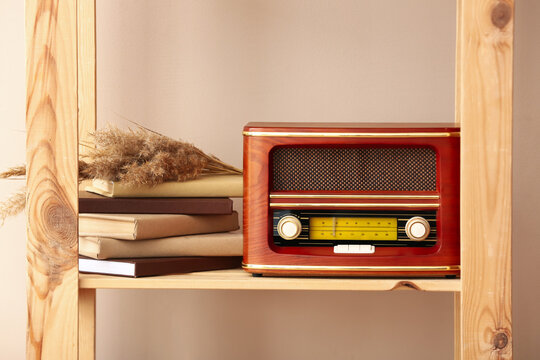 Book shelf with retro radio receiver near color wall