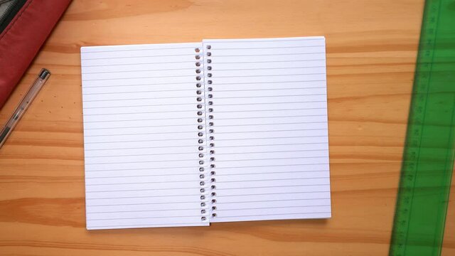 Hands Open Notebook With Empty Pages On The Table. top view