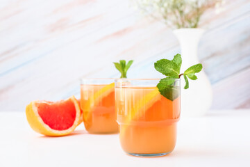 Glasses of tasty grapefruit juice on light background