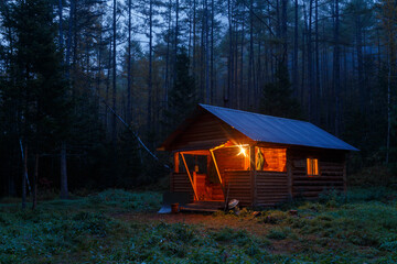 Sikhote-Alin Biosphere Reserve. A wooden hut stands in a dense forest in the middle of the night. The hunter's house of the forester in the Far Eastern taiga.
