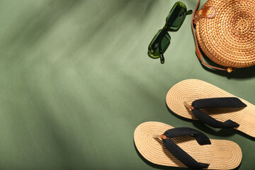 Flip-flops, sunglasses and bag on color background