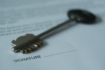 On the table there is a contract and the keys to the room, the emphasis is on the name of the document and the keys. Blurred image.  

