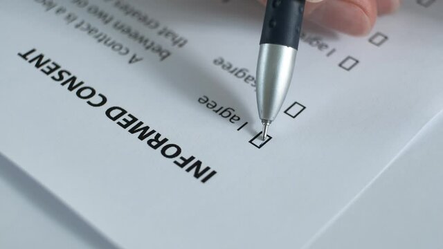 
The client reads the paper document "Informed Consent" , puts a check mark in the "yes"field. Blurred image.