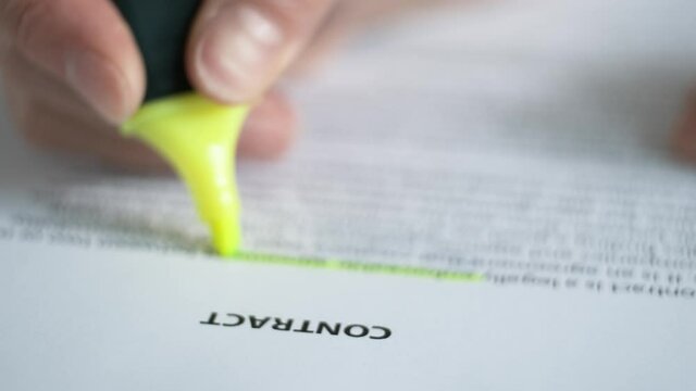 Reading a paper document "Contract", underlining, highlighting the necessary information. Blurred image.