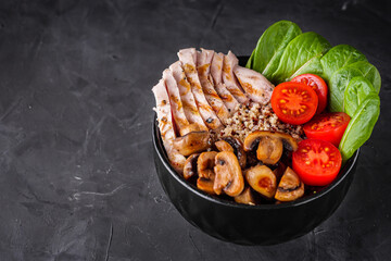 bowl of healthy quinoa with grilled chicken and vegetables on a dark rustic background