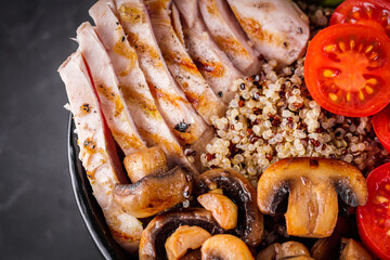 bowl of healthy quinoa with grilled chicken and vegetables on a dark rustic background