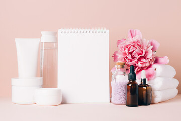 Womens accessories cream oil various cosmetics clean blank notebook on a table with flowers. Beauty concept