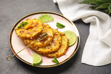 Plate with grilled pineapple slices, honey and lime on dark background