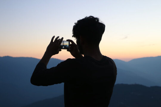 Silhouette Of A Male Taking A Photo On His Phone At Sunset