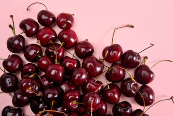 Naklejka na ściany i meble Close up of pile of red cherries with stalks on pink background.