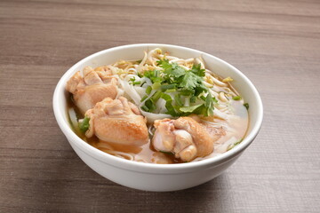 cook clear hot soup with chicken meat, vegetable  and noodle on wood background asian halal menu