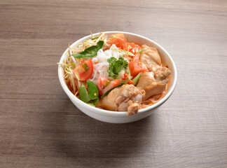 cook curry spicy chilli laksa soup with chicken meat, vegetable  and noodle on wood background asian halal menu