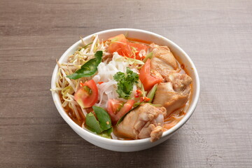 cook curry spicy chilli laksa soup with chicken meat, vegetable  and noodle on wood background asian halal menu