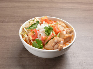 cook curry spicy chilli laksa soup with chicken meat, vegetable  and noodle on wood background asian halal menu