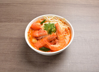 cook curry spicy chilli laksa soup with seafood prawn, vegetable  and noodle on wood background...