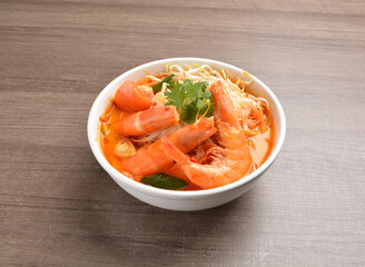 cook curry spicy chilli laksa soup with seafood prawn, vegetable  and noodle on wood background asian halal menu