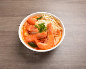 cook curry spicy chilli laksa soup with seafood prawn, vegetable  and noodle on wood background asian halal menu