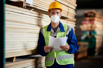 Male worker wearing protective face mask while works at lumber warehouse.