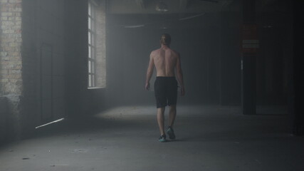 Fototapeta na wymiar Man walking in building after workout. Athlete warming hands before training 