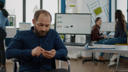 Handicapped, paralyzed immobilized invalid young employee browsing on smartphone during worktime...