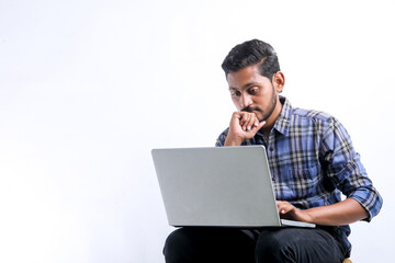 Young indian man using laptop over white background.