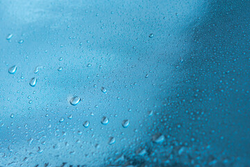 Abstract background with raindrops and beautiful blue bokeh. The concept of autumn and the cold stormy weather. Texture of macro drops on the blurred background of the window. Loneliness sadness