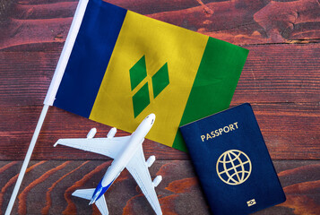 Flag of Saint Vincent and the Grenadines with passport and toy airplane on wooden background....