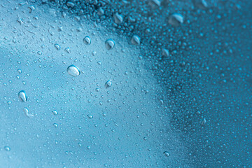 Abstract background with raindrops and beautiful blue bokeh. The concept of autumn and the cold stormy weather. Texture of macro drops on the blurred background of the window. Loneliness sadness
