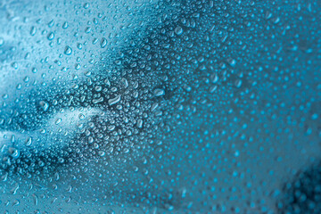 Fototapeta na wymiar Abstract background with raindrops and beautiful blue bokeh. The concept of autumn and the cold stormy weather. Texture of macro drops on the blurred background of the window. Loneliness sadness