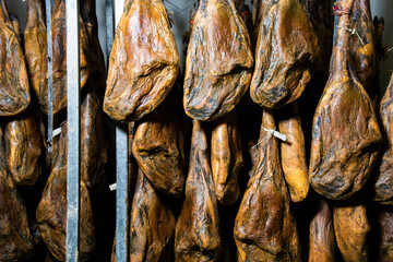 many Iberian Pata Negra hams hung ready to be sold in a warehouse. Jamón serrano. A Spanish ham. Red tag, red label. Iberian Ham