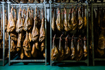 many Iberian Pata Negra hams hung ready to be sold in a warehouse. Jamón serrano. A Spanish ham. Red tag, red label. Iberian Ham