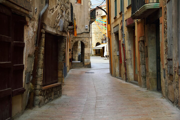 Fototapeta na wymiar Traditional european cityscape - ancient gothic quarter with a cobbled narrow winding street and overhanging walls of houses in Besalu, Girona, Catalonia, Spain, South Europe