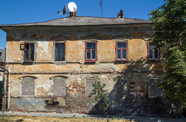 Old crumbling building with satellite dish on the roof.