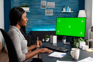 African american student sitting at desk working remote from home during high school online webinar lesson. Black woman searching courses information using mock up green screen chroma key computer