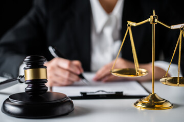 Close up of view Business woman or Female lawyer writing contract paper with Judge gavel, brass scale on a desk at law firm office, law, and justice concept.