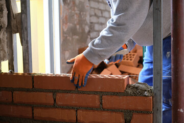 Construction worker building a brick wall. Man bricklaying. Mason laying bricks.