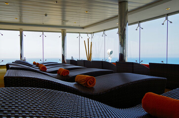 Relaxation room rattan loungers with orange towels inside spa or wellness area thermal suite...